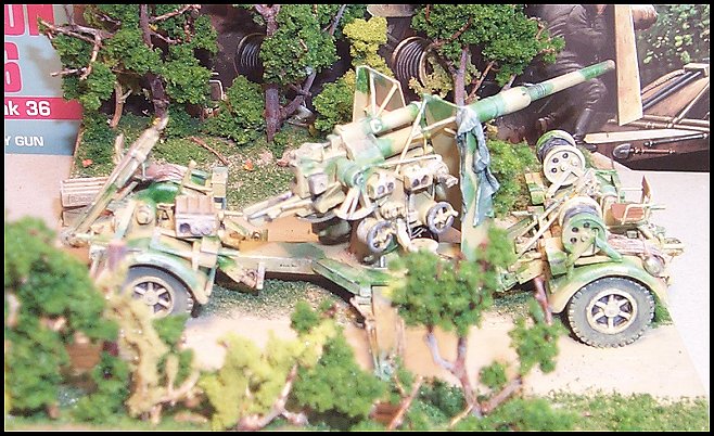 View of the completed model on its display. In the foreground is the hitch for towing the unit. Also note the re-worked and resin copied kit ammunition boxes. Boxes support the outriggers as I have seen in a photo. This also gives a decent view of the scratchbuilt seat and trailer winch. Firing from the trailer put great stress on it and it was best to only fire normal to the trailer (over the wheels) rather than perpendicular (sideways to the wheels).